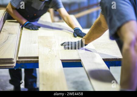 ouvriers assemblant le plancher en bois ensemble dans l'usine Banque D'Images