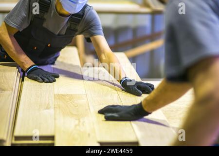 ouvriers assemblant le plancher en bois dans l'usine de transformation du bois Banque D'Images