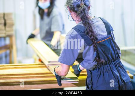 les travailleuses travaillant avec des planches dans l'usine de transformation du bois Banque D'Images