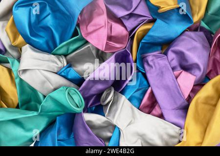 Vue de dessus de fond coloré de texture de ballons dégonflés. Pile de multiples motifs colorés de ballons non soufflés. Tas de ballons dégonflés colorés Banque D'Images