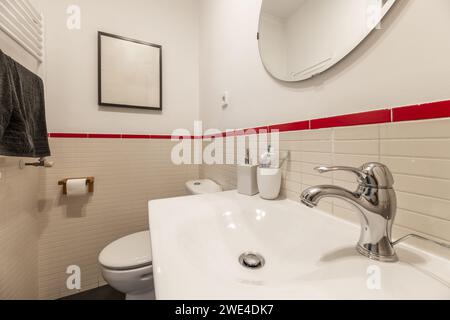 Miroir mural circulaire dans la salle de bains, évier droit en porcelaine d'une seule pièce et robinets en acier inoxydable Banque D'Images