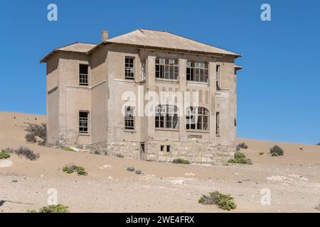 Paysage urbain avec l'ancien bâtiment abandonné de 'Quartermeister' sur sable dans la ville fantôme minière dans le désert, tourné dans la lumière brillante de la fin du printemps à Kolmanskop, Namib Banque D'Images