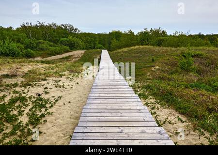 Sentier écologique en bois fait de planches altérées dans les dunes. Chemin direct dans la distance Banque D'Images