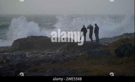 Touristes du Canada, sur le Burren, près du phare de Black Head, dans le comté de Clare en République d'Irlande alors que la tempête Jocelyn frappe. Les efforts visant à rétablir l'alimentation des clients après que l'Irlande ait été battue par la tempête Isha se poursuivent, avec des avertissements de nouvelles perturbations à venir de la tempête Jocelyn. La dernière tempête devrait apporter des rafales allant jusqu'à 65 km/h à partir d'environ 4 heures. Date de la photo : mardi 23 janvier 2024. Banque D'Images