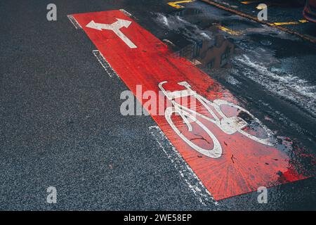 Piste cyclable avec des panneaux fléchés de direction sur la route asphaltée un jour de pluie, mise au point sélective Banque D'Images