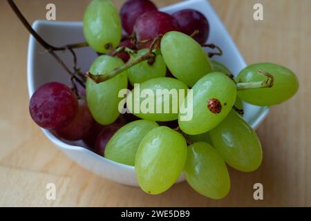 tasse blanche de raisins verts et rouges avec une petite coccinelle rouge Banque D'Images