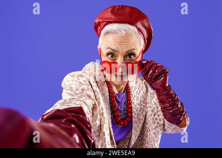 Vieille femme âgée heureuse et drôle portant des vêtements fashinable sur fond coloré- moderne cool portrait de grand-mère fantaisie, concepts sur les personnes âgées et Banque D'Images