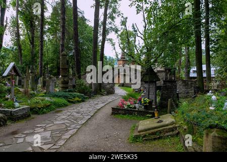 Ancien cimetière (Stary Cmentarz) avec des croix funéraires Goral et vue sur l'église du vieux village (Stary Kościół parafialny) à Zakopane dans les Hautes Tatras in Banque D'Images