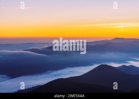 Paysage coloré de la chaîne de montagnes avec brouillard épais dans la vallée au lever du soleil. Banque D'Images