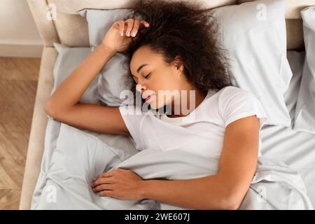 Vue de dessus de la jeune femme noire dormant dans une chambre moderne Banque D'Images
