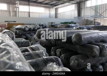 Rouleaux de tissu noir et textiles dans un entrepôt d'usine. Banque D'Images