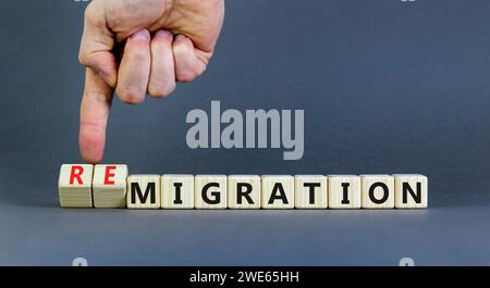 Symbole de migration ou de remigration. Mot concept migration Remigration sur de beaux cubes en bois. Beau fond gris. Main d'homme d'affaires. M Banque D'Images