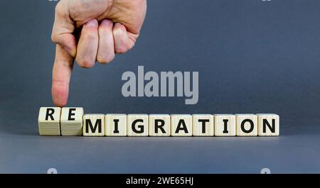 Symbole de migration ou de remigration. Mot concept migration Remigration sur de beaux cubes en bois. Beau fond gris. Main d'homme d'affaires. M Banque D'Images