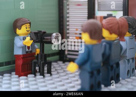 Tambov, Fédération de Russie - 22 janvier 2024 Une minifigure d'homme d'affaires Lego prenant des photos d'hommes d'affaires Lego dans leur bureau. Banque D'Images