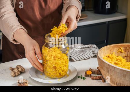 Femme mettant choucroute dans un bocal en verre au comptoir de cuisine Banque D'Images