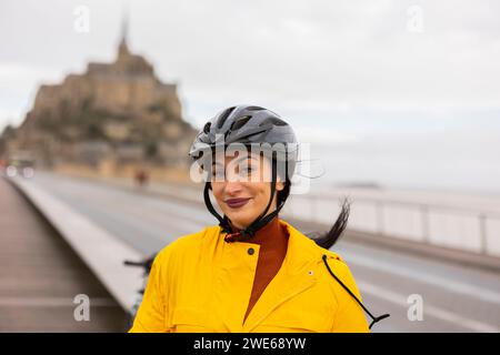 Femme souriante avec casque de vélo dans la rue Banque D'Images