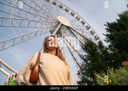 Femme heureuse debout devant la grande roue Banque D'Images
