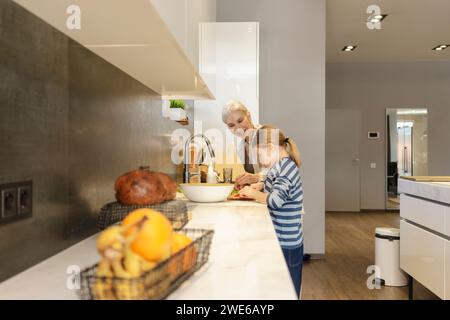 Heureuse grand-mère avec petite-fille préparant la nourriture dans la cuisine à la maison Banque D'Images