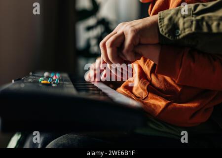 Père enseignant à son fils à jouer du piano électrique à la maison Banque D'Images