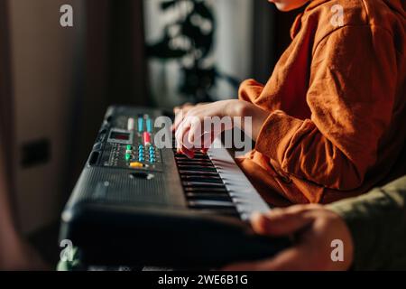 Fils apprenant à jouer du piano électrique avec son père à la maison Banque D'Images