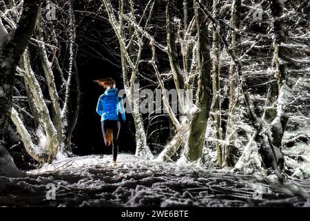 Femme courant dans la forêt d'hiver la nuit Banque D'Images