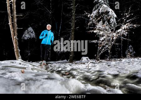 Jeune femme courant dans la forêt d'hiver la nuit Banque D'Images