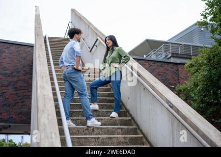 Amis multiraciaux avec les mains sur les hanches debout à l'escalier Banque D'Images