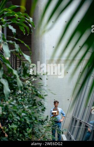 Jeune architecte avec maison modèle debout dans le couloir Banque D'Images