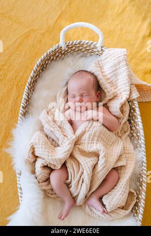 Mignon bébé garçon dormant dans le panier à la maison Banque D'Images