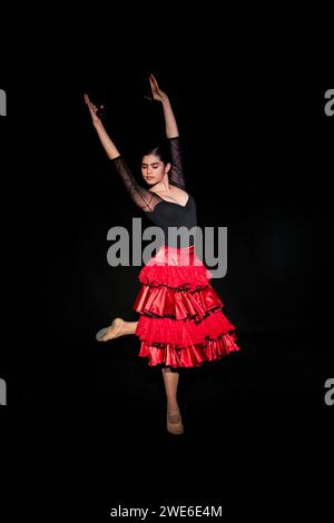 Belle femme faisant de la danse flamenco portant une jupe rouge sur fond noir Banque D'Images