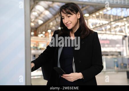 Femme heureuse achetant le billet par la machine à la gare Banque D'Images