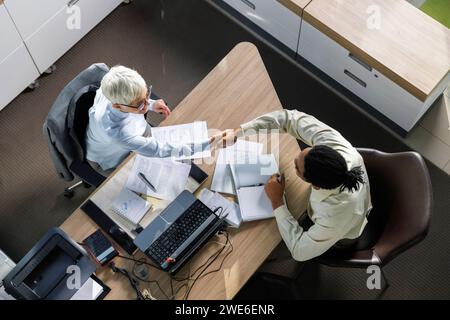 Intervieweur serrant la main au candidat assis au bureau dans le bureau Banque D'Images