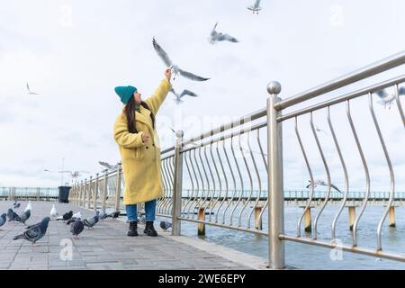 Femme nourrissant des mouettes et des pigeons près de la mer à la promenade Banque D'Images