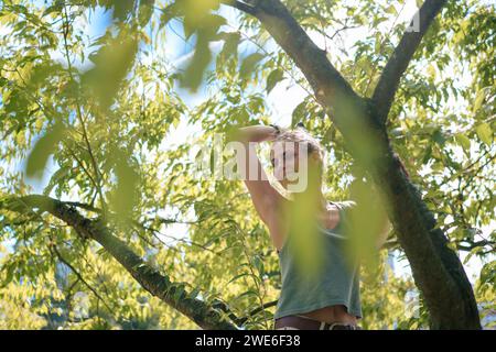 Femme heureuse avec le bras levé debout près de l'arbre Banque D'Images