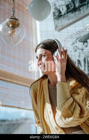 Femme écoutant de la musique avec des écouteurs et se relaxant à la maison Banque D'Images