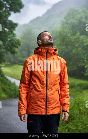 Homme portant une veste orange et debout devant la montagne des Pyrénées Banque D'Images