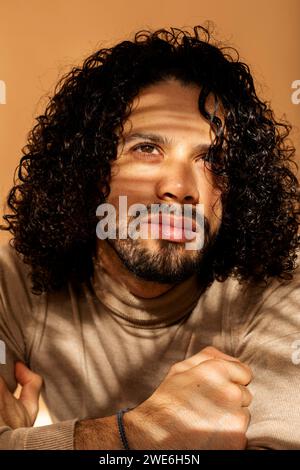 Homme réfléchi avec les cheveux bouclés sur fond orange Banque D'Images