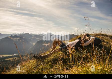 Jeune femme reposant sur le rocher à Tannheimer Tal, Tyrol, Autriche Banque D'Images