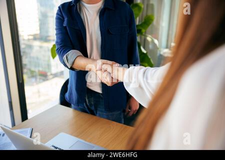 Businessman and businesswoman shaking hands in office Banque D'Images