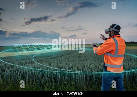 Ingénieur portant des lunettes VR et opérant des panneaux solaires numériques sur le terrain Banque D'Images