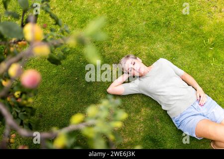 Femme couchée sur l'herbe dans le jardin Banque D'Images