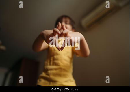 Garçon faisant forme de coeur avec les doigts à la maison Banque D'Images