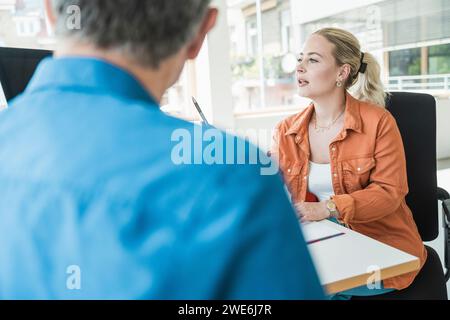 Jeune femme d'affaires discutant avec un collègue au bureau Banque D'Images
