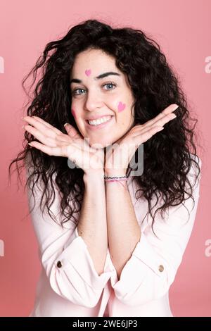 Femme heureuse avec les mains sur le menton et les autocollants en forme de coeur sur le visage Banque D'Images