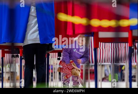 Derry, États-Unis. 23 janvier 2024. Une jeune fille regarde sous le bureau de vote alors qu'un membre de la famille vote à la primaire du New Hampshire sur un site de vote à la Pinkerton Academy à Derry, New Hampshire, le 23 janvier 2024. Le républicain Haley espère devancer l'ancien président américain Donald J. Trump dans les sondages du New Hampshire tandis que le démocrate Dean Phillips espère prendre de l'ampleur contre le président Joe Biden. Photo par Amanda Sabga/UPI crédit : UPI/Alamy Live News Banque D'Images