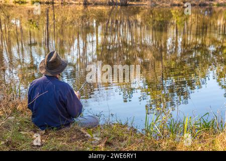 Homme pêchant sur la rive d'un étang privé près de Hattiesburg, Mississippi Banque D'Images