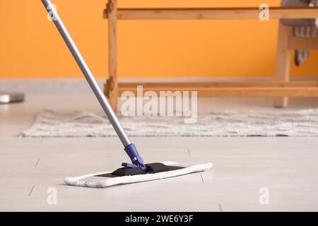 Nettoyage du sol stratifié en bois avec une vadrouille dans le salon Banque D'Images