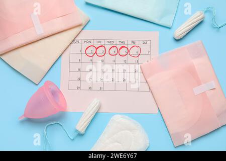 Composition avec calendrier menstruel et produits d'hygiène féminine sur fond de couleur Banque D'Images