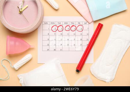 Composition avec calendrier menstruel, réveil et différents produits d'hygiène féminine sur fond de couleur Banque D'Images