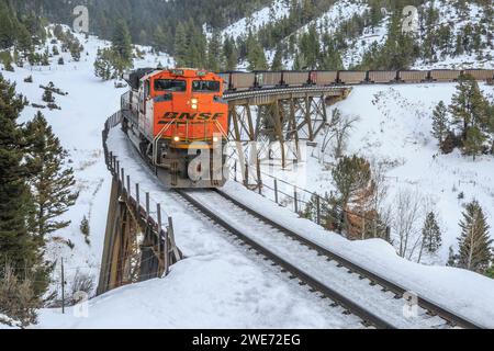 le train transportant des wagons à charbon vers mullan passe au-dessus d'un chevalet en hiver près d'austin, montana Banque D'Images